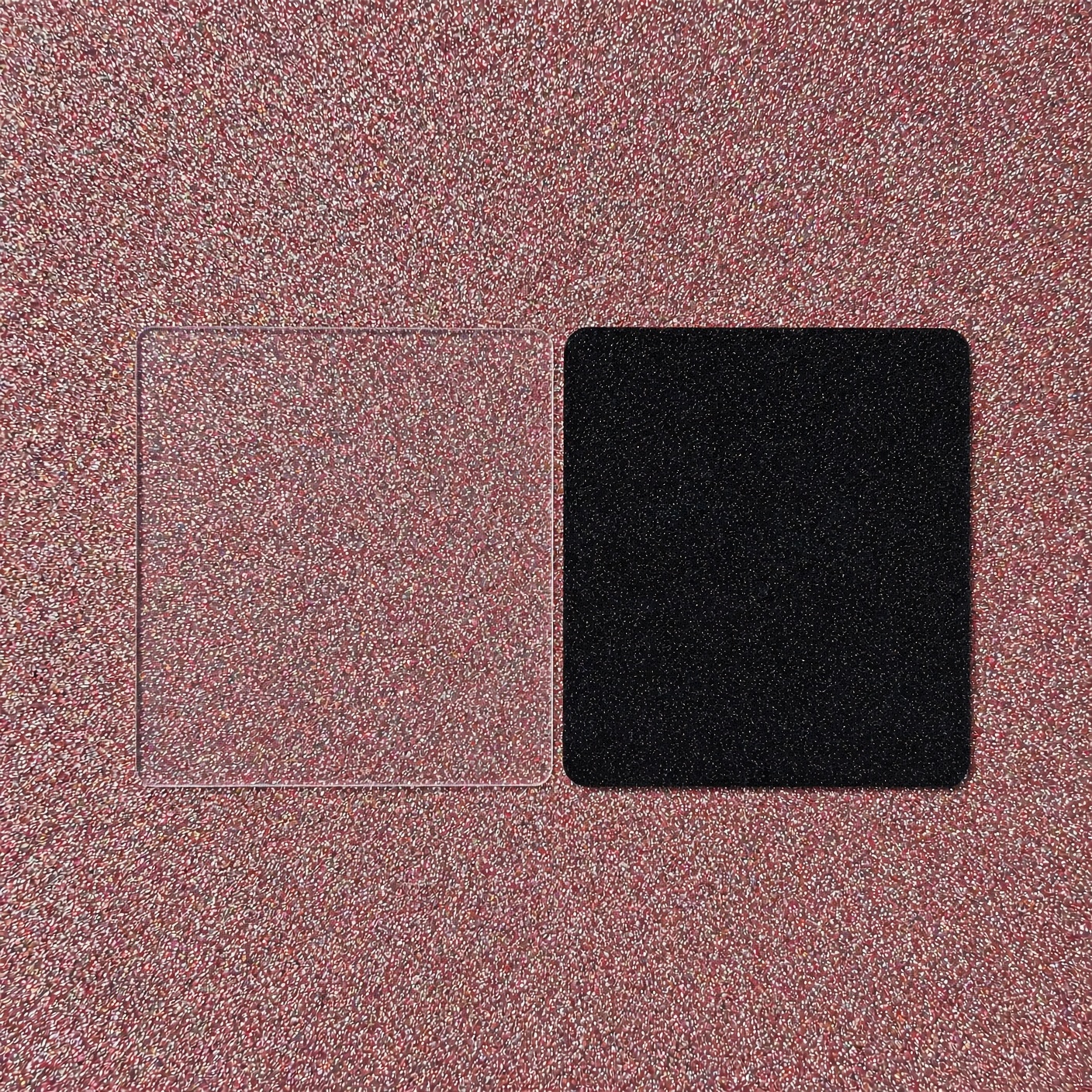 Zwei quadratische Zuschnitte aus PLEXIGLAS® auf rosa Glitzeruntergrund: links farblos transparent, rechts dunkelgrau transparent
