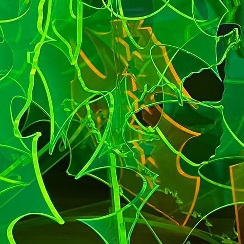 Zuschnitte aus PLEXIGLAS® in Neongrün und Neonorange unter UV-Licht, ihre Kanten leuchten hell