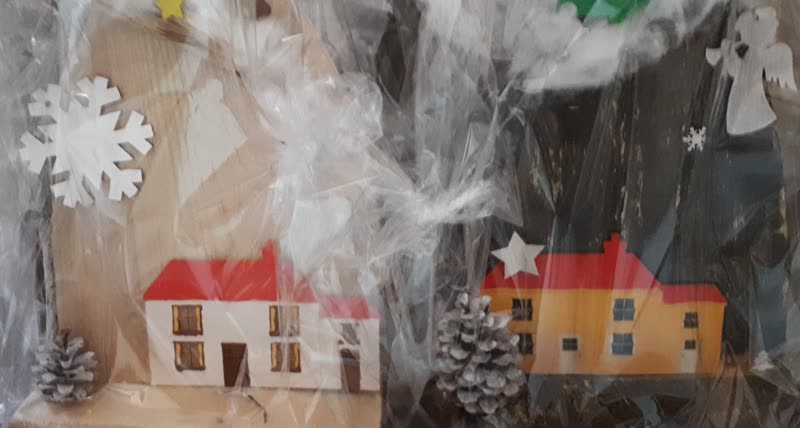 Zwei bemalte Holzhäuschen mit Schneeflocke, Engel und Zapfen, verpackt in Klarsichtfolie