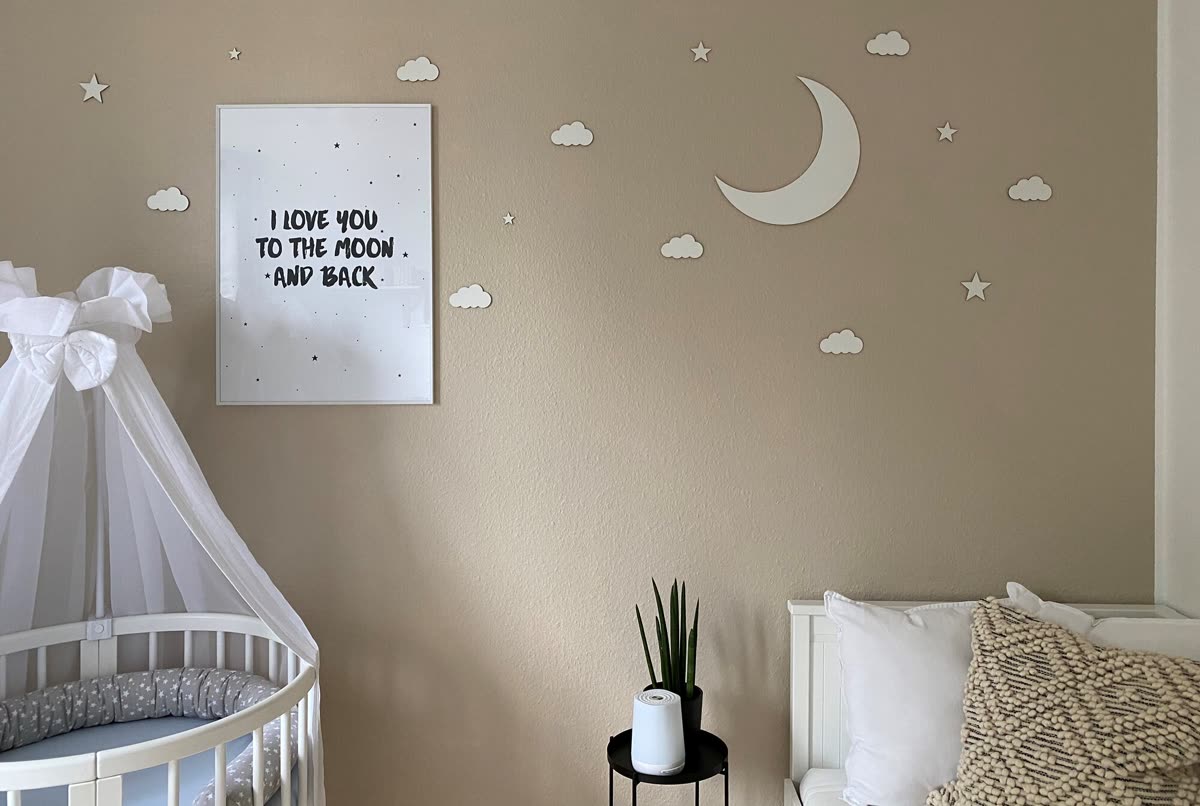 Kinderzimmerwand mit weißem Mond, Wolken und Sternen aus Holz über einem Beistellbett