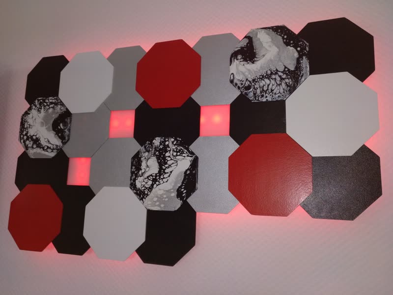 Dieselbe Wandlampe bei Tageslicht: achteckige Platten in Schwarz, Grau und Rot mit gegossenen Marmormustern